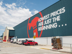 A trade professional in a Bunnings Trade Centre scans a tool barcode with the Power Pass app on a smartphone, amid shelves of equipment.